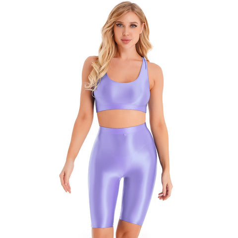 Front view of lady wearing purple sports bra & biker shorts set featuring a sports bra with a racerback cut, thick shoulder straps, and elastic under-bust band, with matching knee-length biker shorts, and a high waist cut for additional tummy support.
