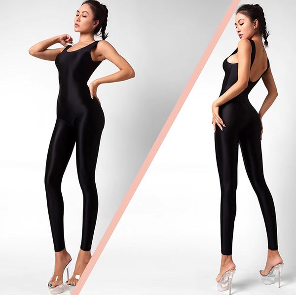 A lady posing in a black catsuit featuring spaghetti straps, a scoop neckline, a low back cut, back zipper closure, and shiny wet look fabric.