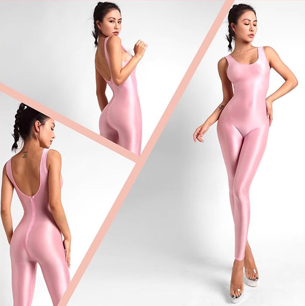A lady posing in a pink catsuit featuring spaghetti straps, a scoop neckline, a low back cut, back zipper closure, and shiny wet look fabric.