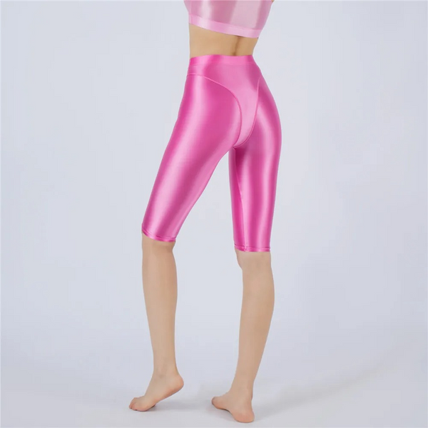 Shiny rose pink shorts worn by a person on a light gray background