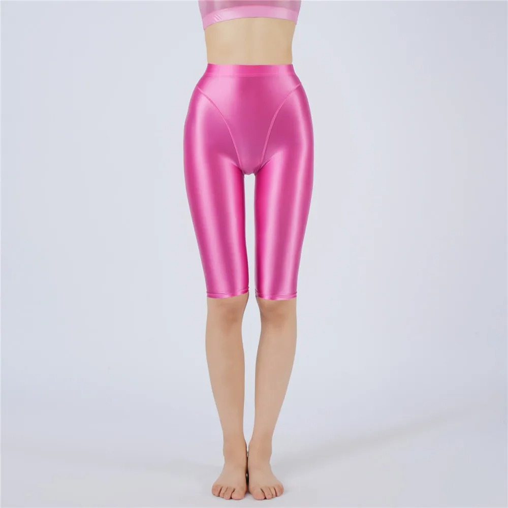 Shiny rose pink shorts worn by a person on a light gray background