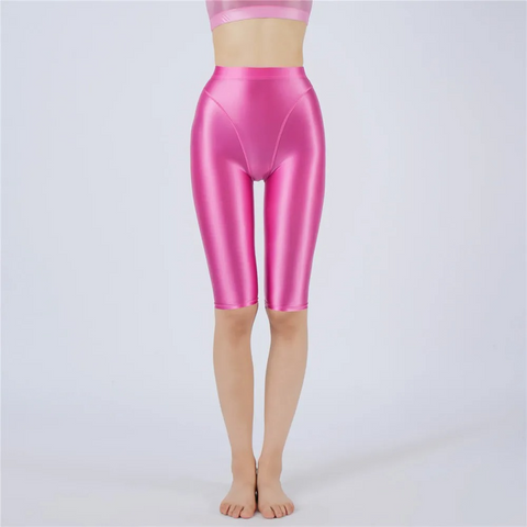 Shiny rose pink shorts worn by a person on a light gray background