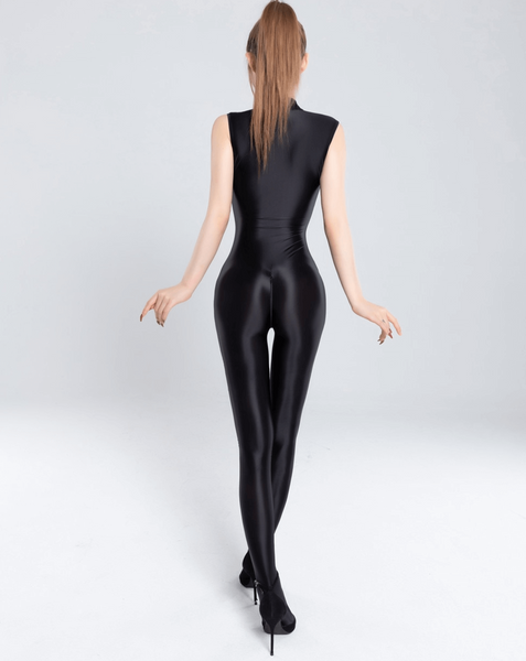 Back view of lady wearing black glossy catsuit with front bust to neck zipper closure, and crotch zipper closure wearing black high heels.