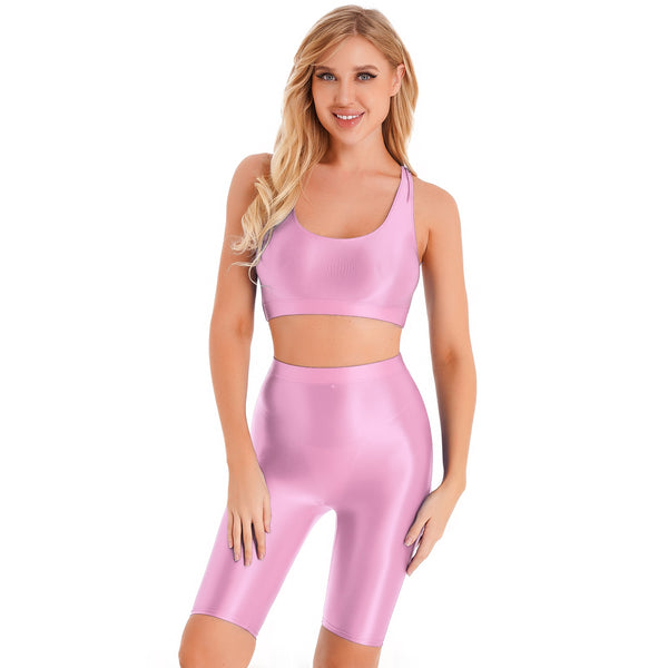 Front view of lady wearing pink sports bra & biker shorts set featuring a sports bra with a racerback cut, thick shoulder straps, and elastic under-bust band, with matching knee-length biker shorts, and a high waist cut for additional tummy support.