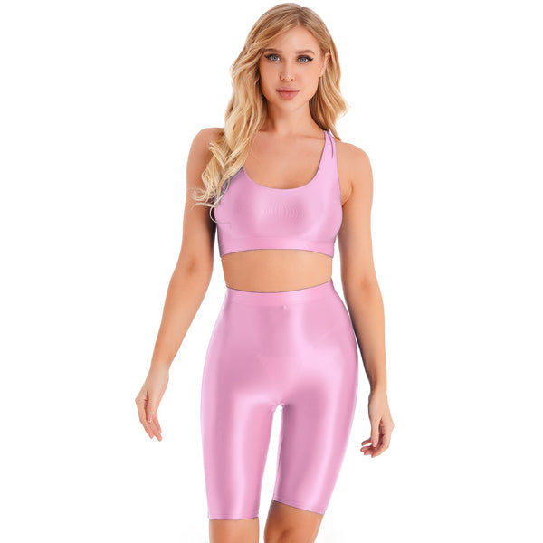 Front view of lady wearing pink sports bra & biker shorts set featuring a sports bra with a racerback cut, thick shoulder straps, and elastic under-bust band, with matching knee-length biker shorts, and a high waist cut for additional tummy support.