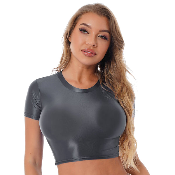 Front view of lady wearing grey crop top featuring a round neckline, short sleeves, and a stretchy and glossy fabric.