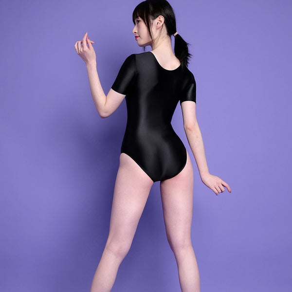 Back view of lady wearing a black wet look leotard featuring a scoop neckline, short sleeves and a cheeky cut back.