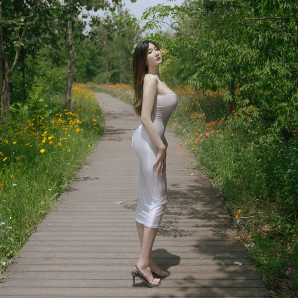 Side view of lady wearing white sheer tube dress, featuring a strapless neckline, and a criss-cross strappy back.