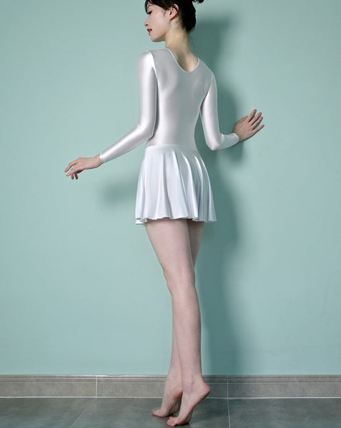Back view of lady wearing white leotard dress featuring a scoop neckline, a scoop back cut, long sleeves, and an attached skirt.