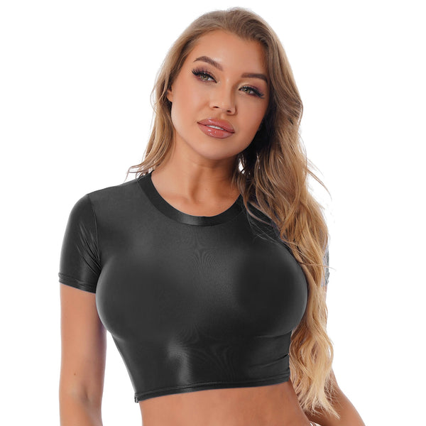 Front view of lady wearing black crop top featuring a round neckline, short sleeves, and a stretchy and glossy fabric.
