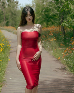 Front view of lady wearing red sheer tube dress, featuring a strapless neckline, and a criss-cross strappy back.