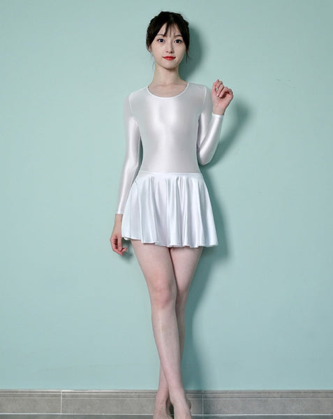 Front view of lady wearing white leotard dress featuring a scoop neckline, a scoop back cut, long sleeves, and an attached skirt.