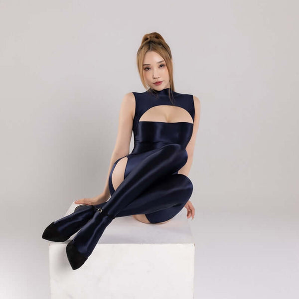front view of lady wearing midnight blue wet-look shiny dress featuring a high neckline, bust cut-out, back zipper closure, and matching gartered thigh high stockings with black high heels