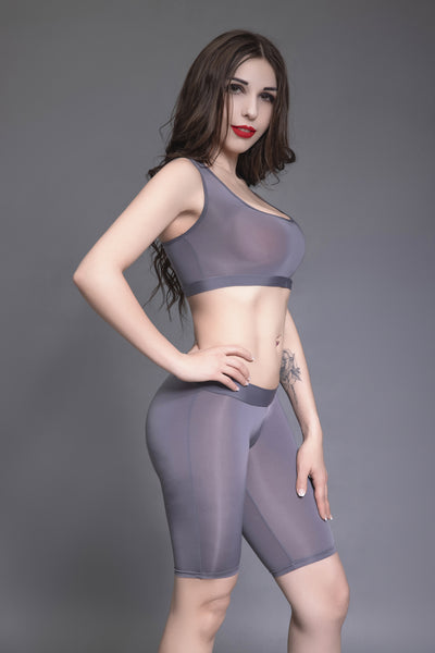 Front view of lady wearing gray color sports bra and matching biker shorts.