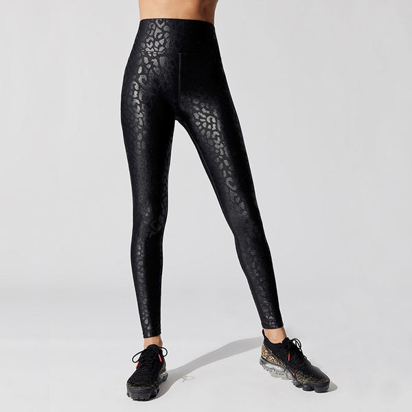 Front view of lady wearing black high waist leggings with shiny leopard prints and ankle length.
