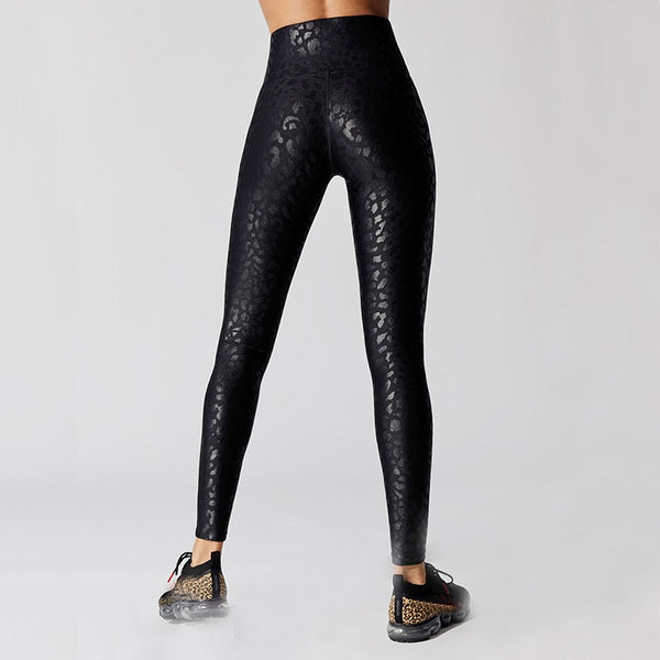 Back view of lady wearing black high waist leggings with shiny leopard prints and ankle length.