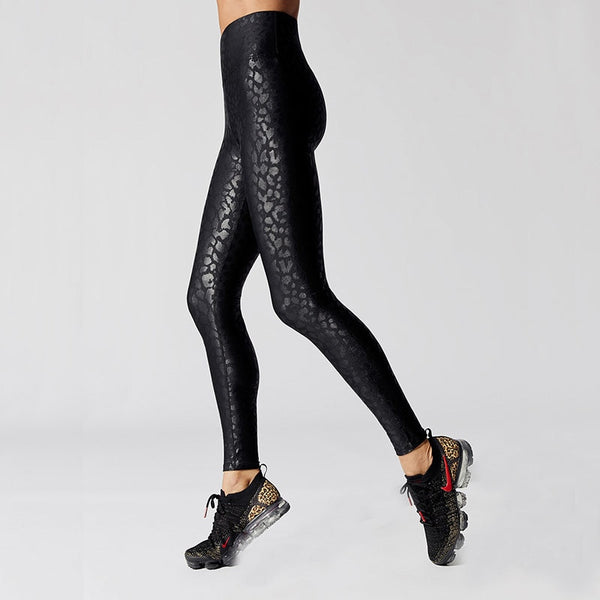 Side view of lady wearing black high waist leggings with shiny leopard prints and ankle length.